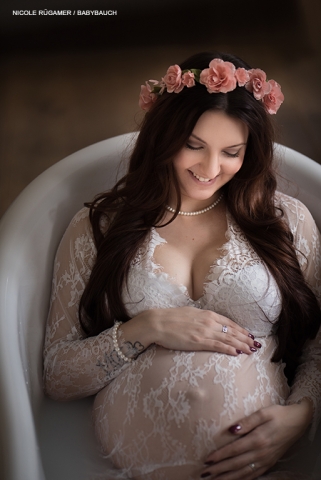 schwanger Frau in Badewanne mit Blumen und weisen Spitzenkleid